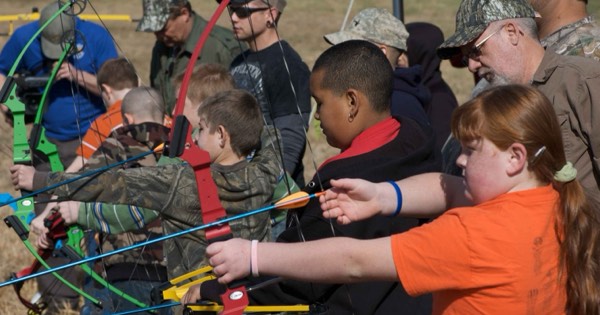 Group of young students at the shooting line practising with colourful beginner bows