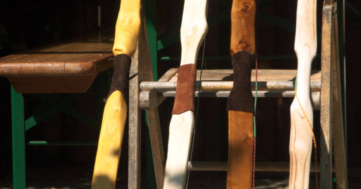 Several unfinished ash flatbows standing in a rack