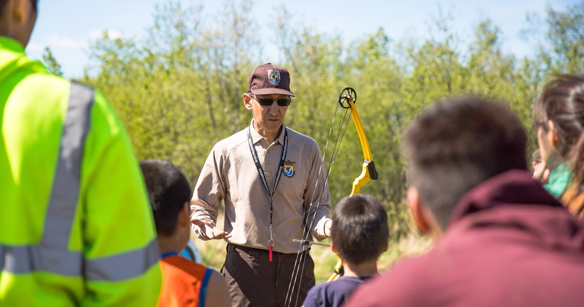 An instructor explaining technique to a group of new archers outdoors