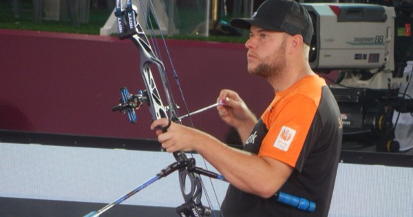 A compound archer nocking an arrow and seating it on the arrow rest before a shot