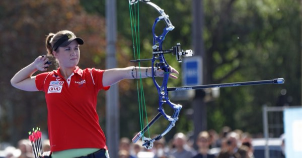 Compound archer at full draw with a long front stabilizer and side rods fitted to the bow
