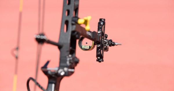 Close-up of a compound bow sight with magnifying scope and bubble level