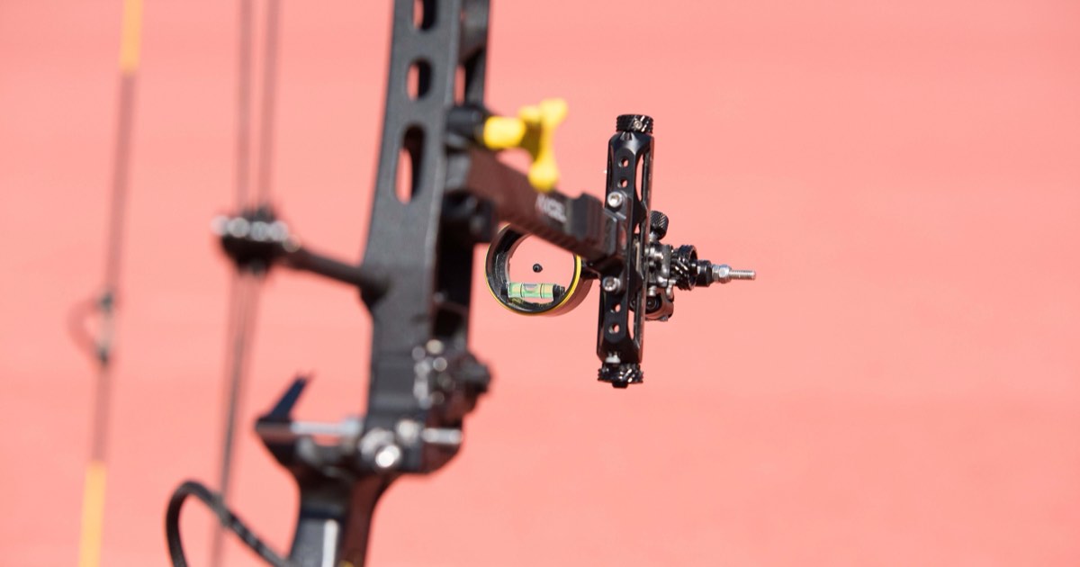 Close-up of a compound bow sight with magnifying scope and bubble level