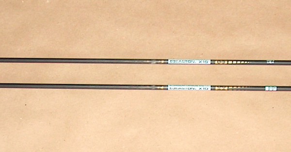 Two Easton X10 competition arrows with yellow fletchings lying on a table