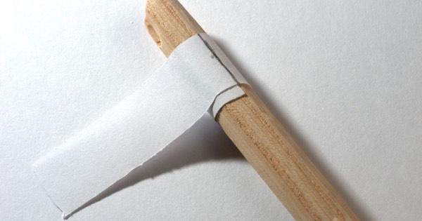 Paper template wrapped around a wooden arrow shaft to mark fletching positions