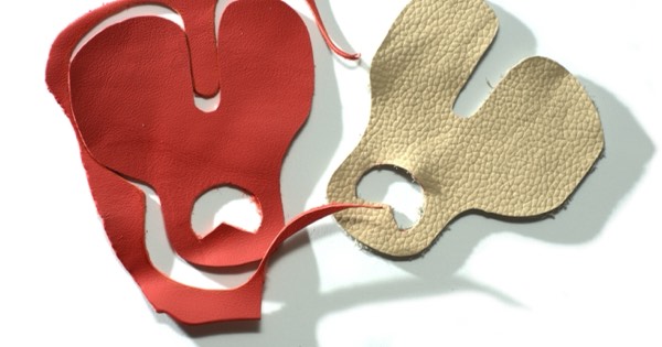 Two leather archery finger tabs, one red and one tan, laid flat
