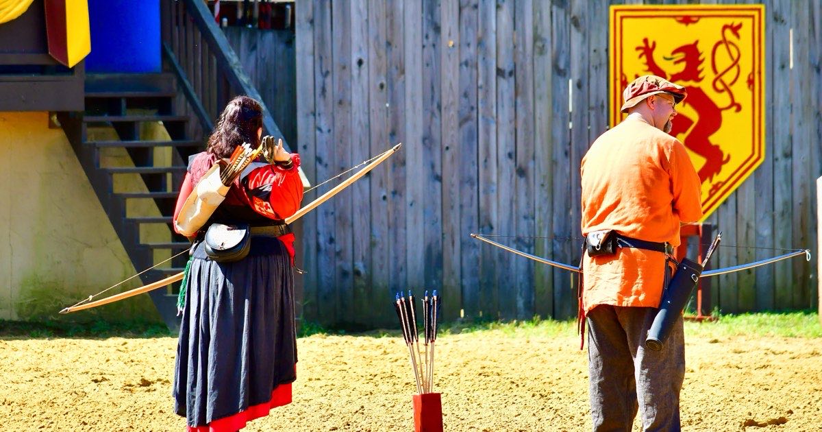Two traditional archers with longbows and arrows at the shooting line