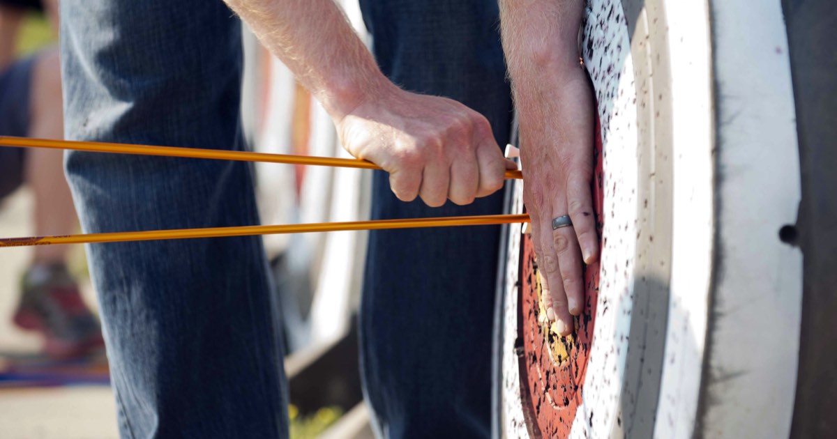 Close-up of hands pulling an arrow out of a target boss