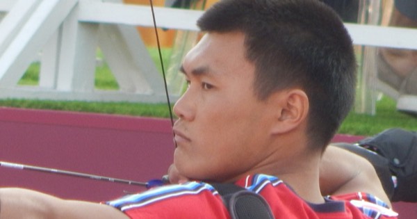 Side profile of a recurve archer at full draw with the string anchored under the chin
