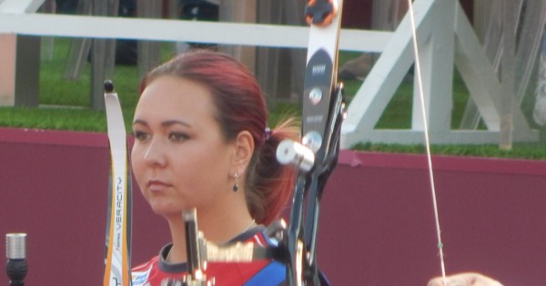 Recurve archer at the shooting line with the riser, sight and clicker visible on an Olympic-style bow