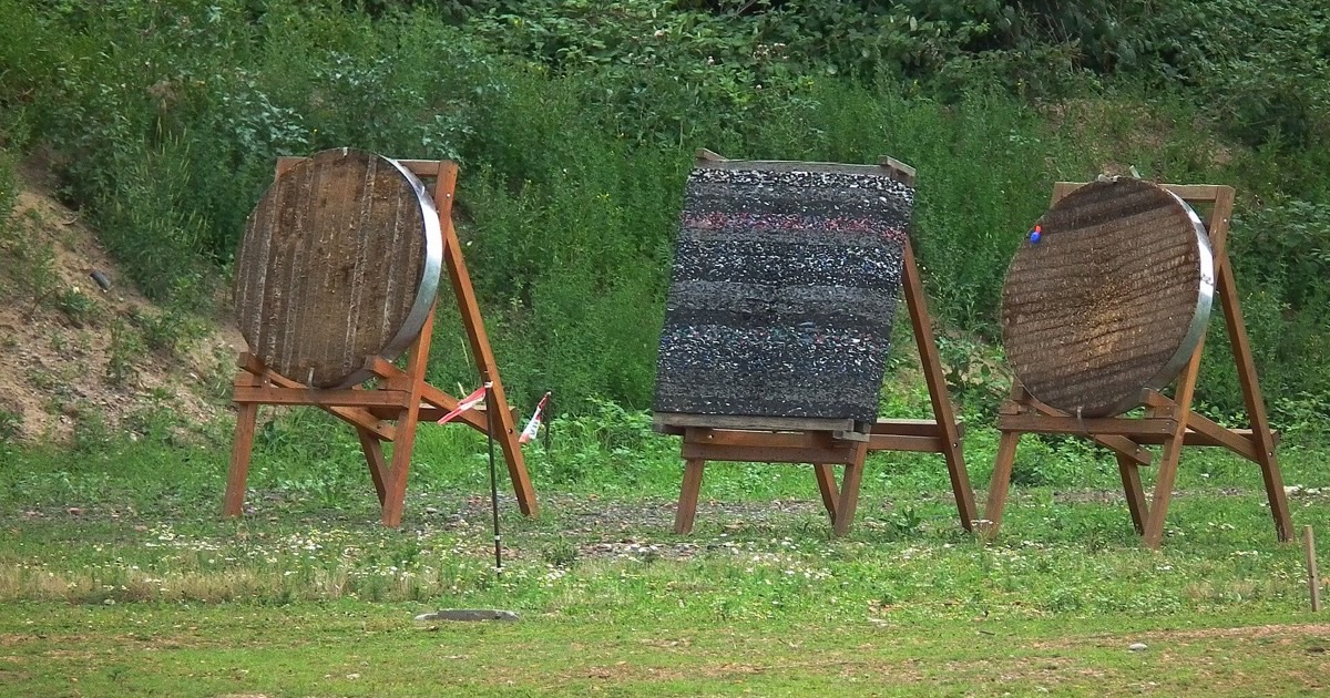 Two round straw target bosses and a layered foam target on wooden stands at an outdoor range