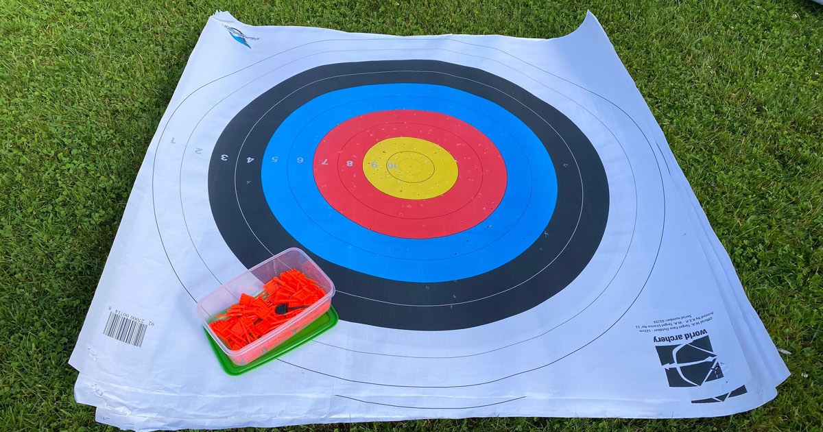 Stack of World Archery 122 cm target faces lying on grass with a box of target pins