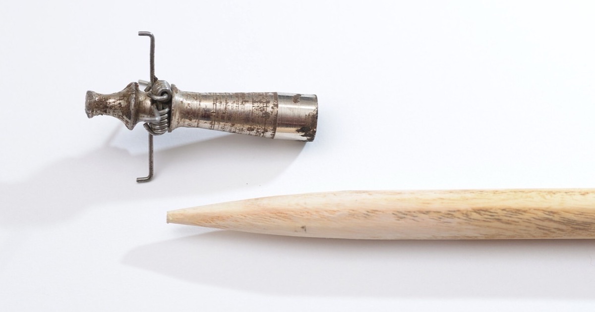A wooden arrow shaft with a tapered end beside a metal glue-on arrow point