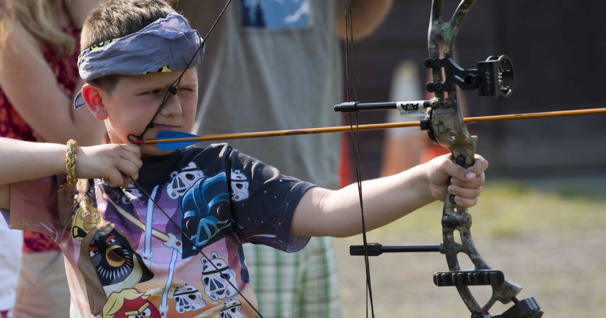 A young archer at anchor with a compound bow, string touching the face